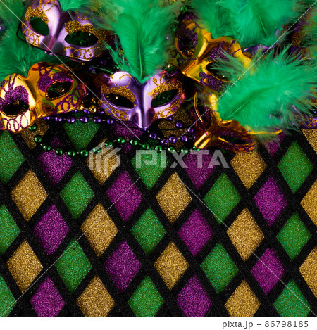 Frame of Mardi Gras Mask and colorful Mardi Gras Beads on diamond shaped background Frame of Mardi Gras Mask and colorful Mardi Gras Beads on diamond shaped background 86798185