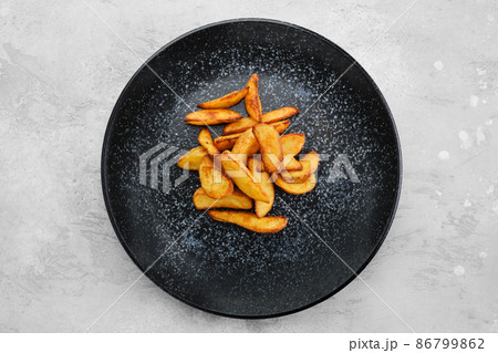 Garnish to the main dish - slices of potato wedges fried in oil, top view Garnish to the main dish - slices of potato wedges fried in oil, top view 86799862