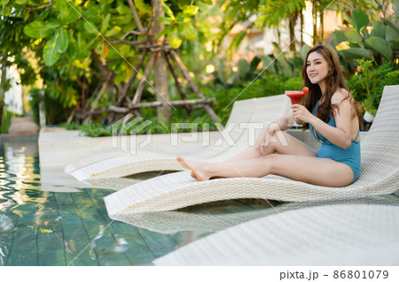 happy woman in swimsuit enjoying with a fresh cocktail at poolside of the swimming pool 86801079