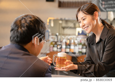 ビールを提供する女性スタッフと男性客 ビールを提供する女性スタッフと男性客 86803069
