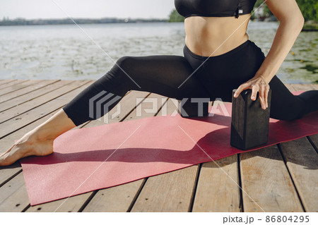 Woman practicing advanced yoga by the water Woman practicing advanced yoga by the water 86804295