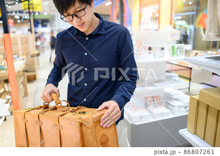 Asian man carrying antique leather suitcase 86807261