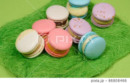 baked macarons with different flavors on a green background, top view baked macarons with different flavors on a green background, top view 86808466