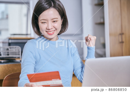 預金通帳を見てガッツポーズをする若い女性 86808850