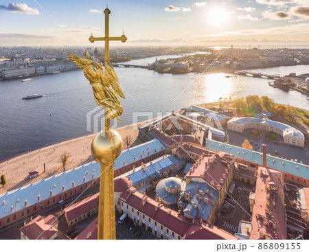 Aerial view of golden Angel and Cross on spike of the Peter and Paul cathedral in Saint Petersburg at sunset, frozen Neva River, sunny frosty day, Winter Palace, Admiralty, Rostral columns Aerial view of golden Angel and Cross on spike of the Peter and Paul cathedral in Saint Petersburg at sunset, frozen Neva River, sunny frosty day, Winter Palace, Admiralty, Rostral columns 86809155