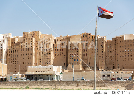 【イエメン】ハドラマウト、世界遺産シバーム・ハドラマウトの石造りの高層建築群と旗めく旧南イエメン国旗 86811417