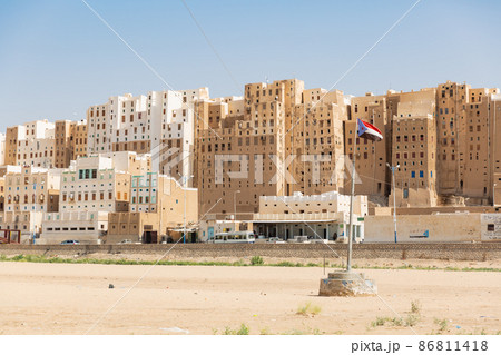 【イエメン】ハドラマウト、世界遺産シバーム・ハドラマウトの石造りの高層建築群と旗めく旧南イエメン国旗 86811418