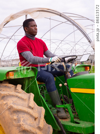African-american worker farmer working on tractor in orangery 86813572