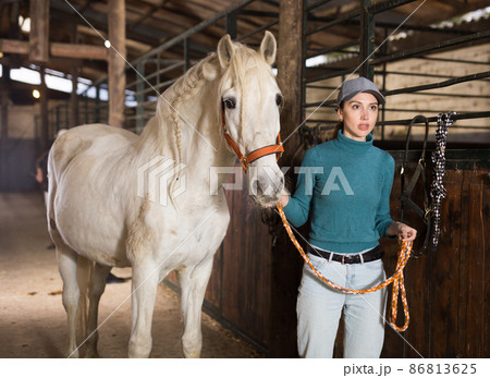 Portrait of woman with white horse in stable 86813625