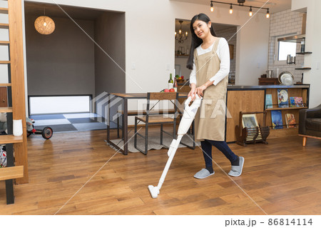 ハンディー掃除機でリビングの掃除をする若い女性 ハンディー掃除機でリビングの掃除をする若い女性 86814114