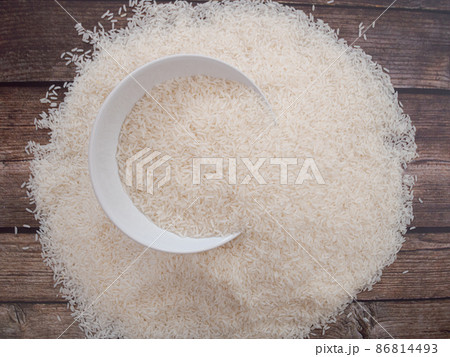 Close up top view rice in a white bowl and scattered near on wooden table with copy space for text and design 86814493
