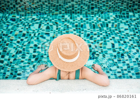 Happy woman in green swimsuit and hat in swimming pool at luxury hotel against ocean front. young female enjoy in tropical resort. Relaxing, summer, travel, holiday, vacation and weekend concept Happy woman in green swimsuit and hat in swimming pool at luxury hotel against ocean front. young female enjoy in tropical resort. Relaxing, summer, travel, holiday, vacation and weekend concept 86820161