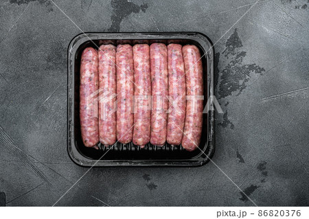 Raw meat sausages in packing box, on gray stone table background, top view flat lay Raw meat sausages in packing box, on gray stone table background, top view flat lay 86820376