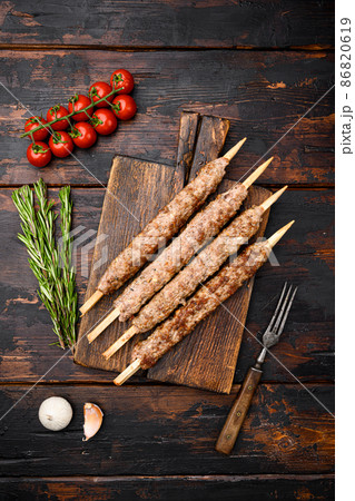 Lula kebab on skewers, on serving board, on old dark wooden table background, top view flat lay Lula kebab on skewers, on serving board, on old dark wooden table background, top view flat lay 86820619