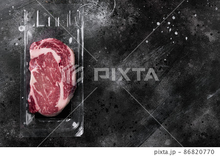 Vacuum plastic pack with fresh beef steak, on black dark stone table background, top view flat lay, with copy space for text 86820770