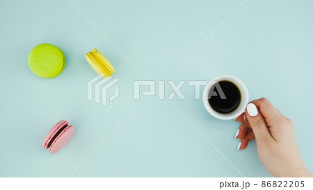Top view of multicolored French Macarons cookies and a cup of coffee on a pastel blue background 86822205