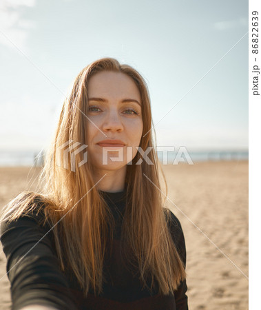 Beautiful woman with long hair, blonde taking selfie on mobile phone on sandy beach in summer 86822639