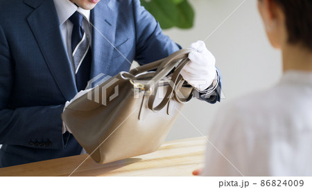 バッグを査定する鑑定士と客 86824009