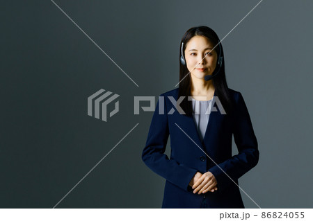 スーツ姿でヘッドセットをつけた笑顔の若い女性オペレーター スーツ姿でヘッドセットをつけた笑顔の若い女性オペレーター 86824055