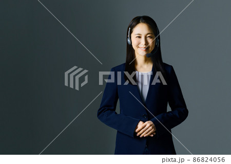 スーツ姿でヘッドセットをつけた笑顔の若い女性オペレーター スーツ姿でヘッドセットをつけた笑顔の若い女性オペレーター 86824056