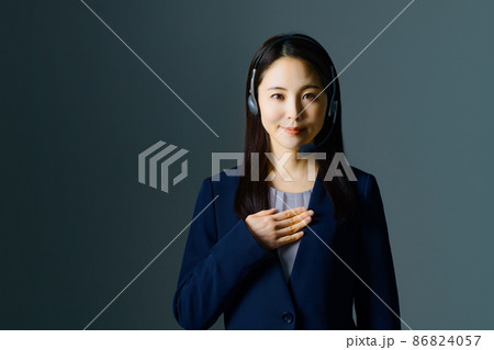 スーツ姿でヘッドセットをつけた笑顔の若い女性オペレーター 86824057