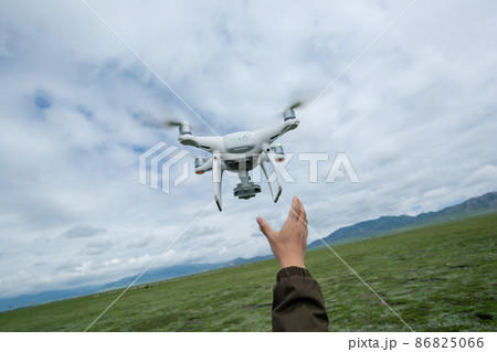Hand reaching for a flying drone taking picture in Tibet,China Hand reaching for a flying drone taking picture in Tibet,China 86825066