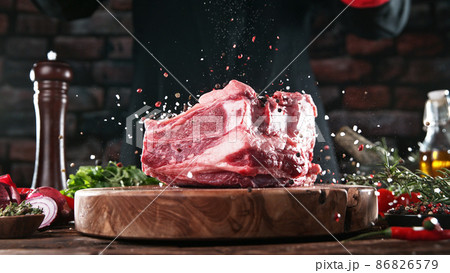Chef pouring grained salt and pepper spice on raw meat steak 86826579