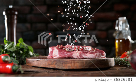 Falling grained salt and pepper spice on raw meat steak 86826581