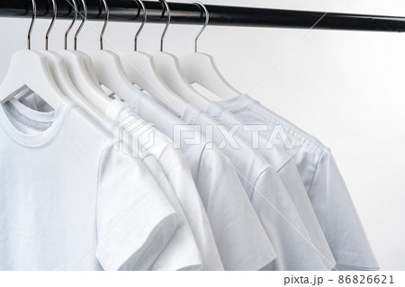 Clothes hang on clothing rack over white background. Clothes hang on clothing rack over white background. 86826621