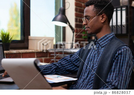 Portrait of african american startup owner with glasses analyzing marketing indicators on clipboard 86828037