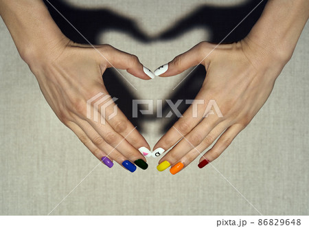 Hands making heart shape with shadow. LGBT rainbow flag and rose triangle manicure. Symbol of lesbian, gay, bisexual, transgender and queer pride isolated.  86829648