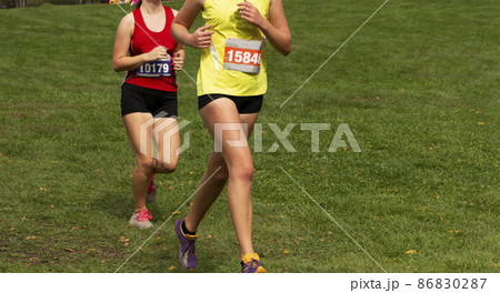 Two girls running a 5K race on grass Two girls running a 5K race on grass 86830287