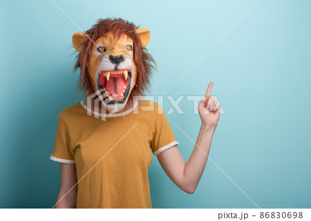 Woman in lion mask pointing with hand and index finger to the side blank space, isolated on blue 86830698