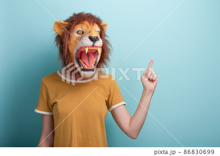 Woman in lion mask pointing with hand and index finger to the side blank space, isolated on blue  86830699