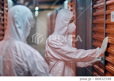 Two people in hazmat suits standing in the storehouse 86832598