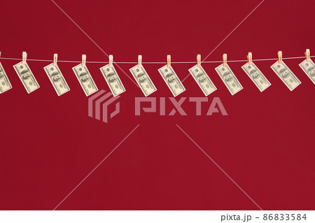 Money laundering, US dollars hanging on rope over red studio background Money laundering, US dollars hanging on rope over red studio background 86833584