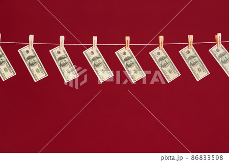 Money laundering, US dollars hanging on rope over red studio background Money laundering, US dollars hanging on rope over red studio background 86833598