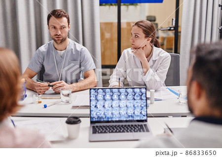 Young confident surgeon looking at one of colleagues during medical concilium 86833650