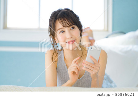 自宅の寝室でスマホを操作する若い女性 自宅の寝室でスマホを操作する若い女性 86836621