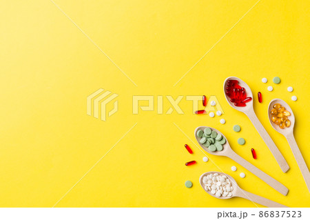 Top view Variety of vitamin and mineral pills in wooden spoon on Colored background. Top view of assorted pharmaceutical medicine pills. Dietary supplement healthcare product Top view Variety of vitamin and mineral pills in wooden spoon on Colored background. Top view of assorted pharmaceutical medicine pills. Dietary supplement healthcare product 86837523