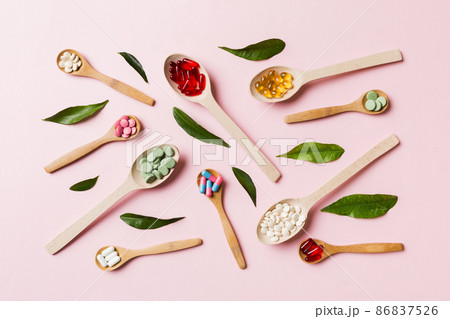Top view Variety of vitamin and mineral pills in wooden spoon on Colored background. Top view of assorted pharmaceutical medicine pills. Dietary supplement healthcare product Top view Variety of vitamin and mineral pills in wooden spoon on Colored background. Top view of assorted pharmaceutical medicine pills. Dietary supplement healthcare product 86837526