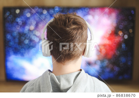 Boy in headphones watching television, teenager boy playing video game in front of screen at home 86838670
