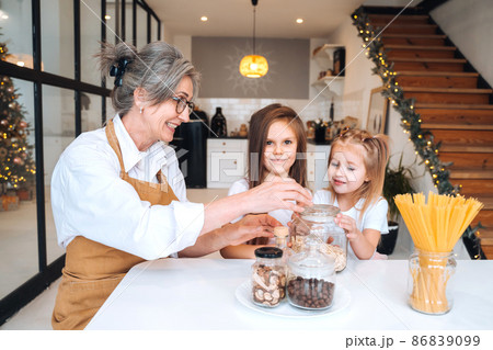 Grandmother and granddaughter are cooking on kitchen. Grandmother and granddaughter are cooking on kitchen. 86839099