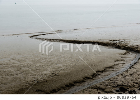 Mud grooves at the beach and shallow waters of the Atlantic Ocean in Lisbon, Portugal on a foggy day. Mud grooves at the beach and shallow waters of the Atlantic Ocean in Lisbon, Portugal on a foggy day. 86839764