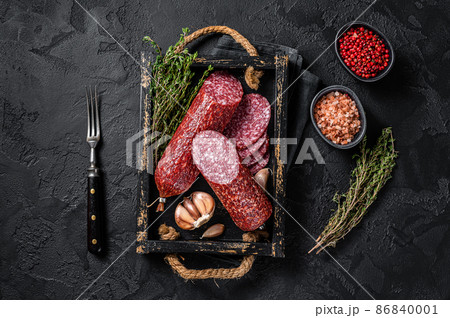 Sliced Dry salami sausage with fresh thyme. Black background. Top view Sliced Dry salami sausage with fresh thyme. Black background. Top view 86840001