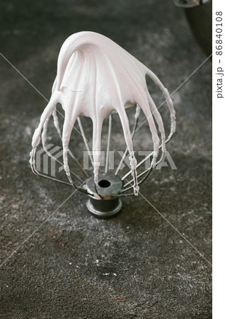 Whipped egg whites - beaten italian meringue on a wire whisk on gray background, copy space. 86840108