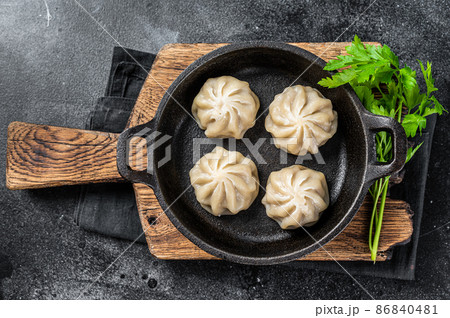 Dim sum stuffed meat dumplings in a pan with herbs. Black background. Top view 86840481