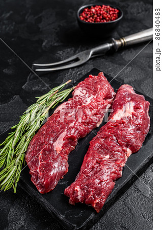 Raw Machete steak or hanging tender cut with herbs. Black background. Top view 86840483