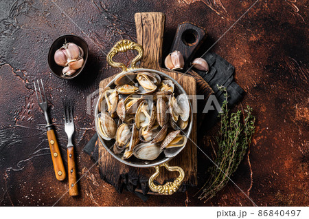 Garlic white wine shells Clams, vongole in a skillet with herbs. Dark background. Top view Garlic white wine shells Clams, vongole in a skillet with herbs. Dark background. Top view 86840497