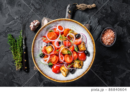 Vegetarian salad Panzanella with tomatoes, onion and bread Croutons. Black background. Top view Vegetarian salad Panzanella with tomatoes, onion and bread Croutons. Black background. Top view 86840604
